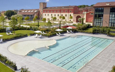 Panoramablick auf den Außenbereich des Hotels Veronesi La Torre, mit einem gepflegten Pool und einer weitläufigen Terrasse, umgeben von grünen Gärten.