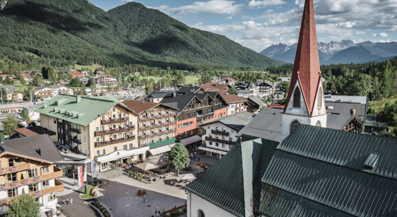 Elegante Fassade des Post Seefeld Hotel & Spa in Seefeld, umgeben von einer malerischen Berglandschaft.