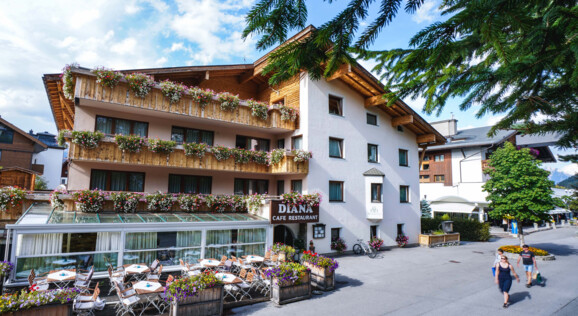 Fassade des Hotel Diana in Seefeld, umgeben von alpiner Landschaft und grünen Wiesen