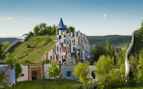 Bunte, außergewöhnliche Fassade des Hotel Bad Blumau, umgeben von der malerischen Landschaft der Steiermark