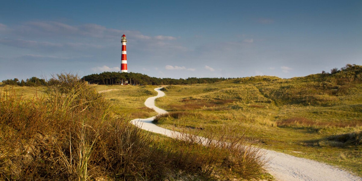 Der markante Leuchtturm auf Ameland, einer der friesischen Inseln in den Niederlanden, umgeben von Küstenlandschaft.