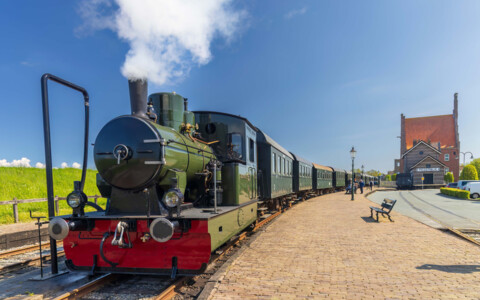 Historischer Dampfzug fährt durch die Landschaft in Medemblik, eine reizvolle Fahrt durch die niederländische Umgebung.