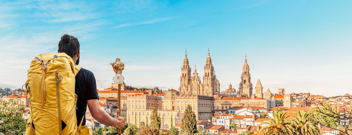 Ein Pilger erreicht das Ziel in Santiago de Compostela, mit Blick auf die imposante Kathedrale, die das Ende des Jakobswegs markiert