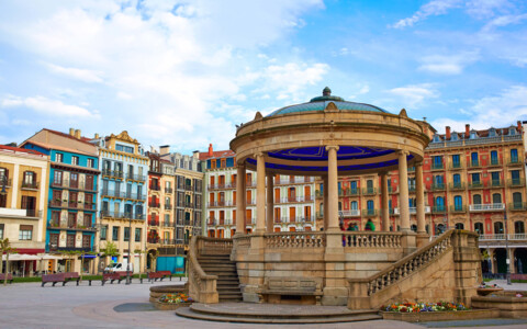 Der belebte Plaza del Castillo in Pamplona, umgeben von historischen Gebäuden und Cafés, ein zentraler Treffpunkt der Stadt.