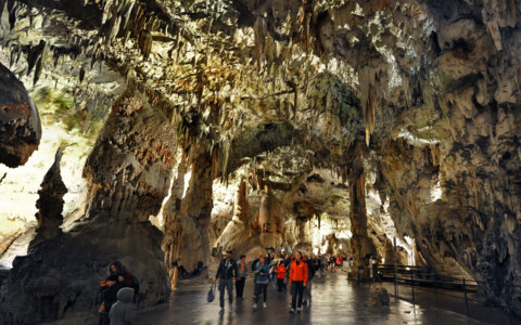 Imposante Stalaktiten und Stalagmiten in der Postojna-Höhle in Slowenien, mit einem unterirdischen Bahnweg für Besucher.