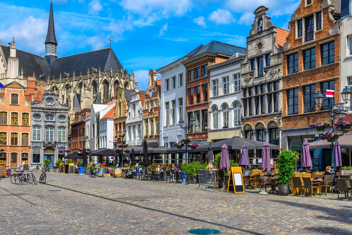 Ein zentraler Platz in Mechelen, Belgien, umgeben von historischen Fassaden und einer lebhaften Atmosphäre.