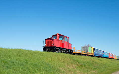 Die historische Inselbahn von Langeoog, die durch die Dünenlandschaft fährt und eine beliebte Möglichkeit bietet, die Insel zu erkunden.