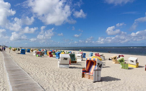 Der weitläufige Sandstrand auf Langeoog, umgeben von Dünen und Strandkörben, ideal für entspannende Tage am Meer.