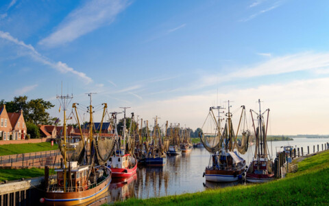 Der malerische Kutterhafen von Greetsiel, mit traditionellen Fischkuttern und historischen Hafenhäusern, die das maritime Flair des Ortes unterstreichen.