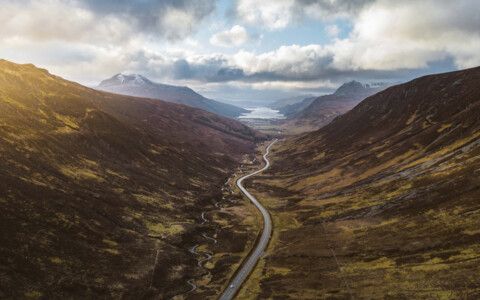 Das idyllische Loch Maree bei Kinlochewe, umgeben von sanften Hügeln und dichten Wäldern, eine ruhige Wasserfläche in den schottischen Highlands