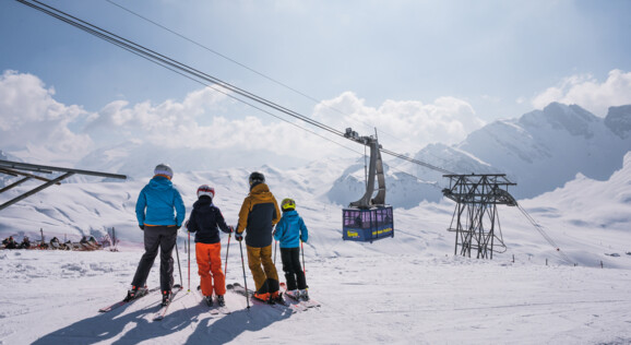 Gruppe von Skifahrern im Skigebiet Melchsee-Frutt – perfekt für Gruppenreisen und Schulausflüge, mit speziellen Gruppenpreisen und Angeboten für Schulen. Die Bergbahn im Hintergrund sorgt für komfortable Anreise mit Bus- und Carfahrt ins Skigebiet