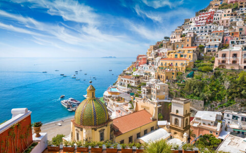 Das charmante Dorf Positano an der Amalfiküste, mit pastellfarbenen Häusern, die sich steil den Berghang hinunterziehen, bis hinunter zum türkisblauen Meer.