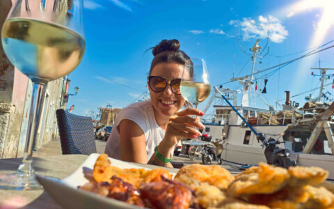 Frau in traditioneller italienischer Umgebung genießt ein Glas Wein, ein typisches Bild für die entspannte Lebensart in Italien.