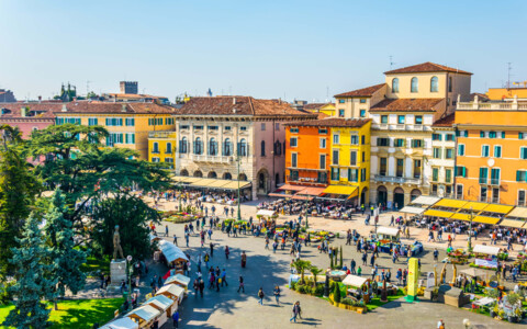 Lebhafter Piazza in Verona, umgeben von historischen Gebäuden und Cafés, mit Brunnen und Platz für Passanten und Einheimische.