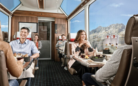 Eleganter Innenraum der 1. Klasse des Glacier Express, mit großen Panoramafenstern und luxuriösen Sitzen, während der Zug durch die Schweizer Alpen fährt.