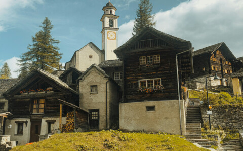 Das Dorf Bosco Gurin liegt idyllisch in einem tiefen Tal umgeben von majestätischen Schweizer Alpen. Die traditionellen Holzhäuser mit ihren charakteristischen Steindächern fügen sich harmonisch in die natürliche Umgebung ein. 