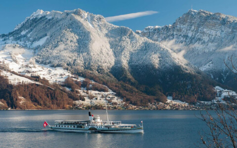 Ein elegantes Schiff gleitet über den Thunersee, umgeben von schneebedeckten Bergen und einer winterlichen Landschaft.