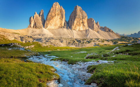 Die imposanten Drei Zinnen, ein berühmtes Bergmassiv in den Dolomiten, mit ihren charakteristischen, steil aufragenden Gipfeln unter klarem Himmel.