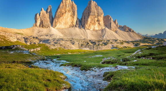 Die imposanten Drei Zinnen, ein berühmtes Bergmassiv in den Dolomiten, mit ihren charakteristischen, steil aufragenden Gipfeln unter klarem Himmel.