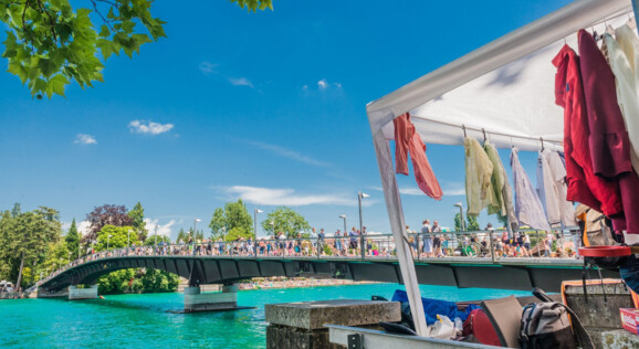 24h Flohmarktstand in Konstanz auf einer Brücke mit Blick auf den Bodensee, umgeben von Besuchern, die Antiquitäten, Kunsthandwerk und Sammlerstücke entdecken.