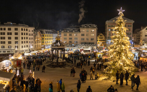 Weihnachtsmarkt Einsiedeln-  Bunte, beleuchtete Marktstände bieten handgemachte Weihnachtsdekorationen, Geschenke und kulinarische Spezialitäten an, umgeben von besinnlicher Weihnachtsmusik.